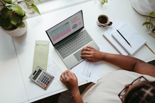 Person reviewing household budget with laptop, notebook and calculator as part of a home loan application