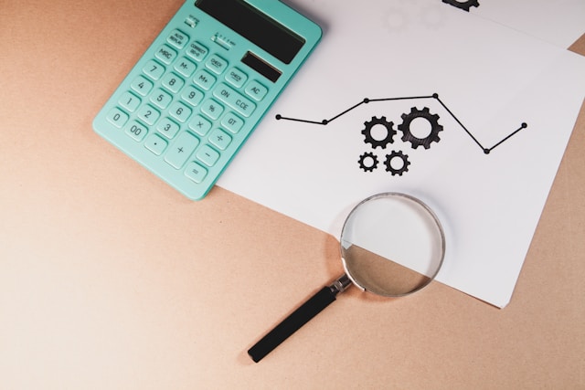 Magnifying glass reviewing financial documents and calculator during a home loan assessment