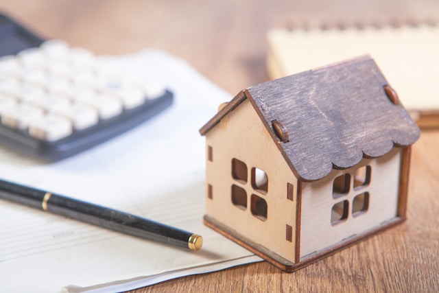 House model with calculator and financial documents representing using home equity instead of a cash deposit